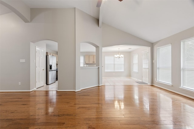 16306 Ancient Forest Dr, Humble, TX 77346 - unfurnished living room with ceiling fan, high vaulted ceiling, a chandelier, light wood-style flooring, and arched walkways