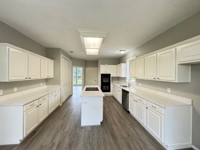 819 Companion Dr, Crosby, TX 77532 - kitchen with black appliances, a kitchen island with sink, dark wood-style flooring, and white cabinets