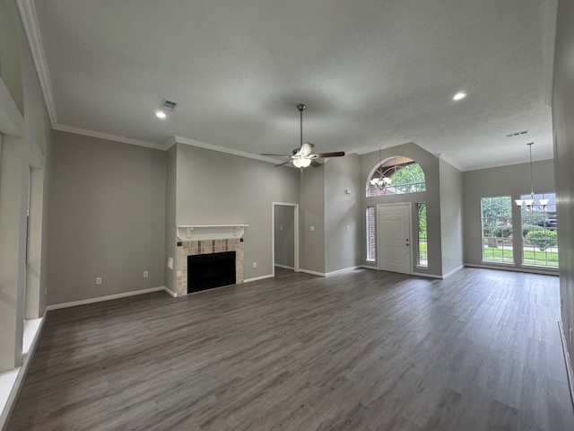 819 Companion Dr, Crosby, TX 77532 - unfurnished living room featuring a chandelier, a ceiling fan, a tiled fireplace, dark wood-type flooring, and ornamental molding