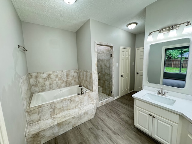 819 Companion Dr, Crosby, TX 77532 - bathroom with a garden tub, vanity, wood finished floors, a shower stall, and a textured ceiling