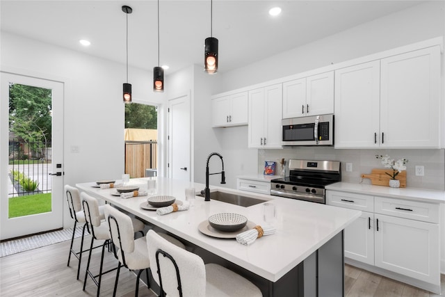 2475 Carmel St A/B, Unit A/B Houston, TX 77091 - kitchen featuring stainless steel appliances, a center island with sink, light countertops, white cabinets, and light wood finished floors