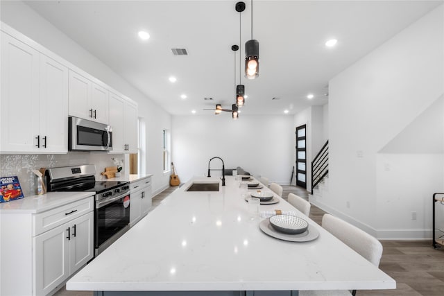 2475 Carmel St A/B, Unit A/B Houston, TX 77091 - kitchen with appliances with stainless steel finishes, a large island, light wood-type flooring, white cabinetry, and backsplash