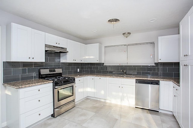 6407 Nuben St, Houston, TX 77091 - kitchen with appliances with stainless steel finishes, under cabinet range hood, light stone counters, backsplash, and white cabinets