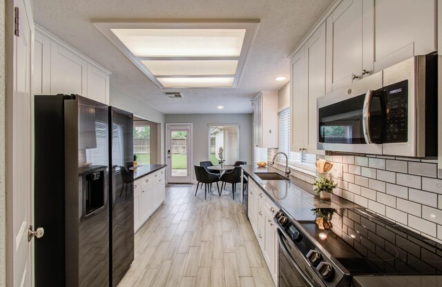 22523 Wildwood Grove Dr, Katy, TX 77450 - kitchen with refrigerator with ice dispenser, stainless steel microwave, range with electric stovetop, dark countertops, and white cabinetry