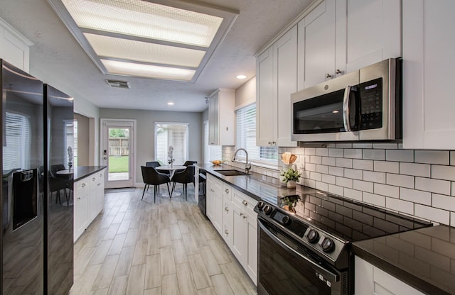 22523 Wildwood Grove Dr, Katy, TX 77450 - kitchen featuring stainless steel microwave, black / electric stove, refrigerator with ice dispenser, dark countertops, and recessed lighting