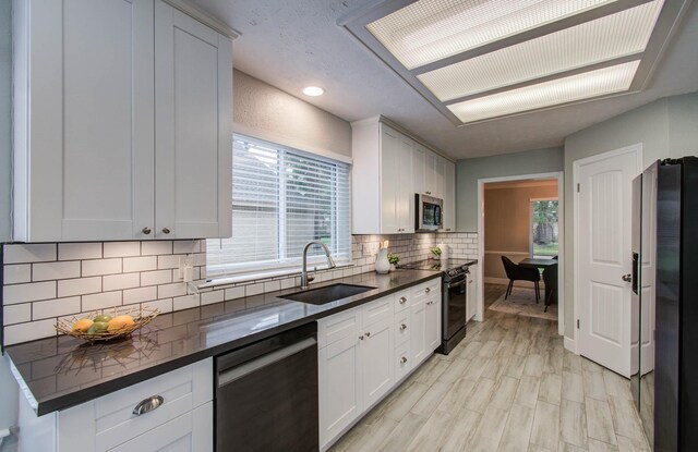 22523 Wildwood Grove Dr, Katy, TX 77450 - kitchen featuring appliances with stainless steel finishes, dark countertops, backsplash, white cabinets, and recessed lighting