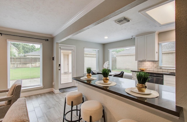 22523 Wildwood Grove Dr, Katy, TX 77450 - kitchen featuring dark countertops, a textured ceiling, a breakfast bar, dishwashing machine, and decorative backsplash