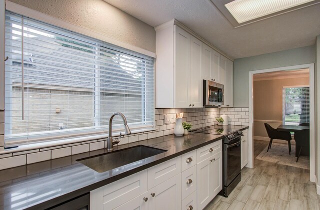 22523 Wildwood Grove Dr, Katy, TX 77450 - kitchen with black range with electric stovetop, stainless steel microwave, backsplash, dark countertops, and white cabinetry