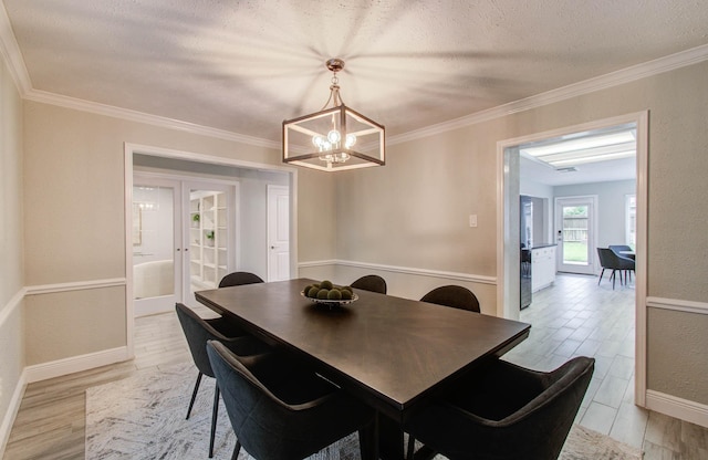 22523 Wildwood Grove Dr, Katy, TX 77450 - dining room featuring light wood-type flooring, a chandelier, crown molding, a textured ceiling, and french doors