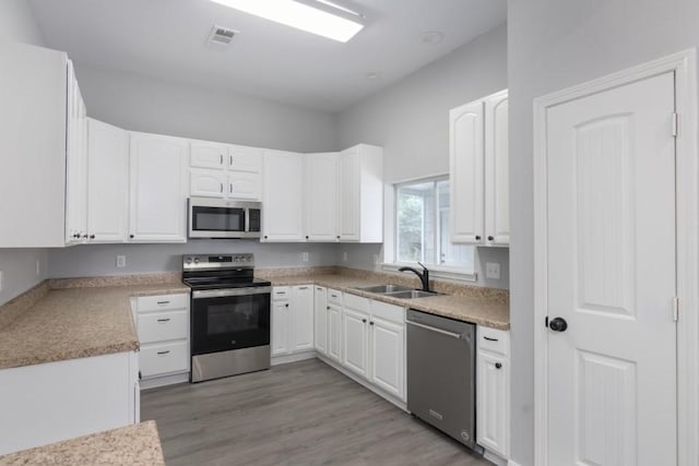 575 Hartman Rd, Silsbee, TX 77656 - kitchen with stainless steel appliances, white cabinets, light wood finished floors, and light countertops