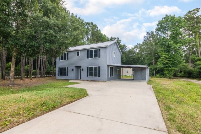 575 Hartman Rd, Silsbee, TX 77656 - colonial home featuring concrete driveway, a front lawn, an attached carport, and a metal roof