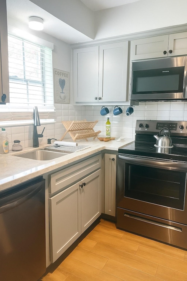 13022 Trail Hollow Dr Unit 3022, Houston, TX 77079 - kitchen featuring appliances with stainless steel finishes, tasteful backsplash, light stone countertops, and light wood-style flooring