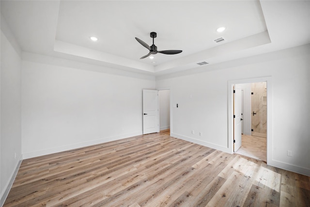19219 Hikers Trail Dr, Humble, TX 77346 - unfurnished bedroom featuring a tray ceiling, light wood-type flooring, recessed lighting, ceiling fan, and connected bathroom