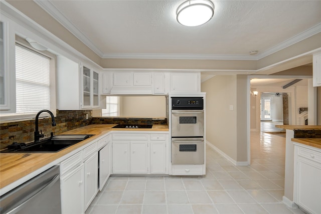 13903 Chevy Chase Dr, Houston, TX 77077 - kitchen with multiple ovens, stainless steel dishwasher, crown molding, glass insert cabinets, and light tile patterned floors