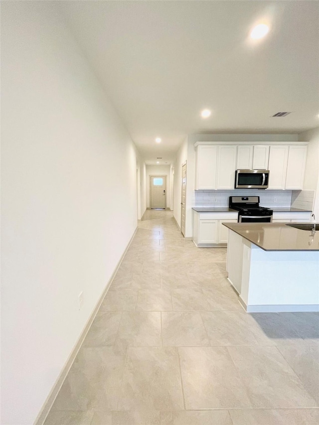 4107 Yosemite Valley Ct, Katy, TX 77494 - kitchen featuring black gas stove, stainless steel microwave, recessed lighting, backsplash, and white cabinets