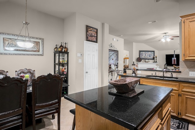 9827 Kimberly Loch Ln, Houston, TX 77089 - kitchen featuring ceiling fan, light tile patterned floors, a center island, tasteful backsplash, and dark stone countertops