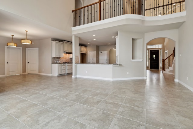 6510 Brady Springs Ct, Sugar Land, TX 77479 - unfurnished living room with arched walkways, a high ceiling, light tile patterned floors, and recessed lighting