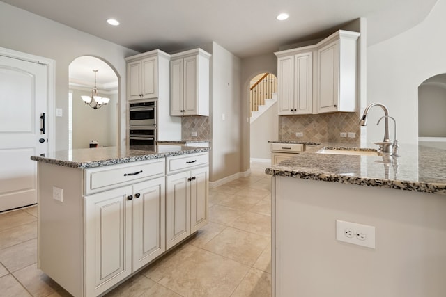 6510 Brady Springs Ct, Sugar Land, TX 77479 - kitchen with arched walkways, stone countertops, backsplash, light tile patterned floors, and recessed lighting
