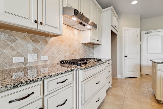 6510 Brady Springs Ct, Sugar Land, TX 77479 - kitchen with under cabinet range hood, stainless steel gas stovetop, light stone countertops, tasteful backsplash, and light tile patterned flooring