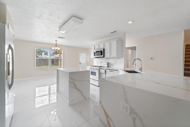 1022 Vera Cruz Dr, Rosenberg, TX 77471 - kitchen featuring stainless steel appliances, a chandelier, a kitchen island, light stone countertops, and light marble finish flooring