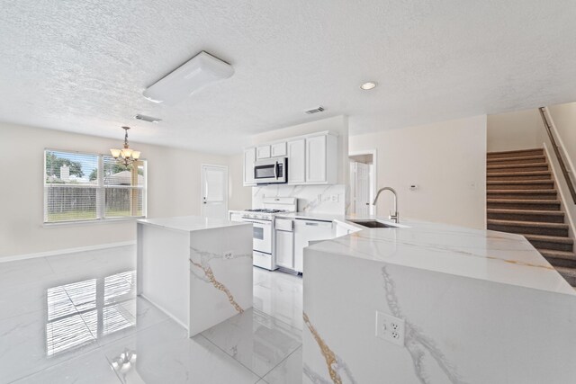 1022 Vera Cruz Dr, Rosenberg, TX 77471 - kitchen featuring white appliances, a center island, a textured ceiling, a chandelier, and white cabinetry