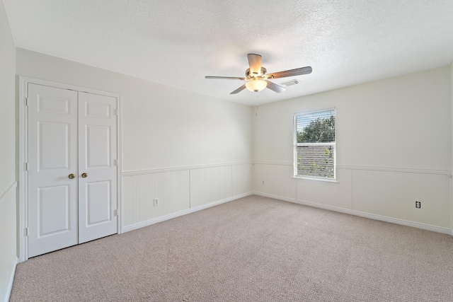 1022 Vera Cruz Dr, Rosenberg, TX 77471 - spare room featuring ceiling fan, carpet flooring, a textured ceiling, and a wainscoted wall