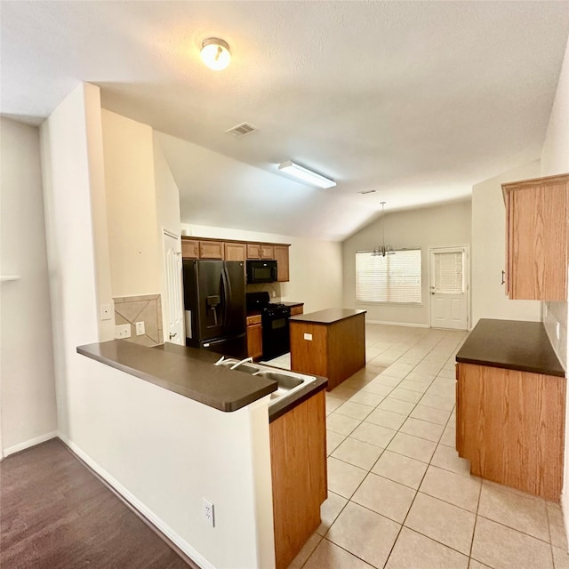 1005 Summer Park Blvd, Conroe, TX 77303 - kitchen featuring black appliances, vaulted ceiling, dark countertops, a kitchen island, and a peninsula