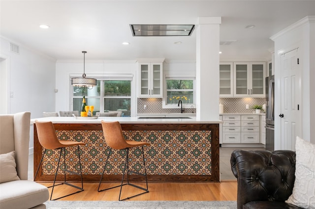 8932 Padfield St, Houston, TX 77055 - bar area featuring stainless steel refrigerator with ice dispenser, light wood-style flooring, decorative backsplash, ornamental molding, and pendant lighting