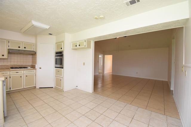 12006 Scottsdale Dr, Meadows Place, TX 77477 - kitchen with oven, under cabinet range hood, light countertops, light tile patterned floors, and a textured ceiling