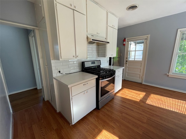 1805 Sul Ross St, Houston, TX 77098 - kitchen featuring stainless steel range with gas stovetop, dark wood-style floors, light countertops, under cabinet range hood, and white cabinetry