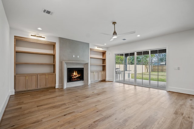 13915 Queensbury Ln, Houston, TX 77079 - unfurnished living room with a lit fireplace, a ceiling fan, recessed lighting, light wood finished floors, and built in shelves