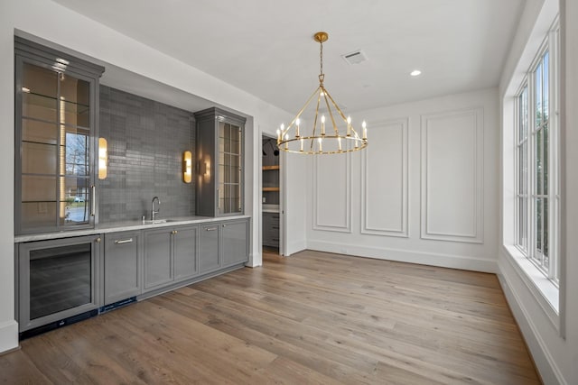 13915 Queensbury Ln, Houston, TX 77079 - unfurnished dining area featuring wine cooler, light wood finished floors, plenty of natural light, a chandelier, and recessed lighting