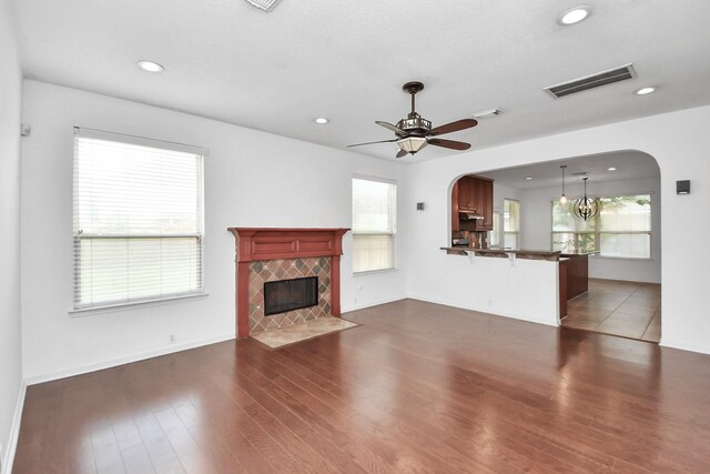 2508 Sun Glen Dr, Pearland, TX 77584 - unfurnished living room featuring arched walkways, dark wood-style flooring, a ceiling fan, a fireplace, and recessed lighting