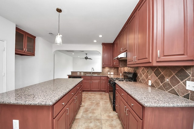 2508 Sun Glen Dr, Pearland, TX 77584 - kitchen with black range with gas stovetop, under cabinet range hood, tasteful backsplash, light stone countertops, and ceiling fan