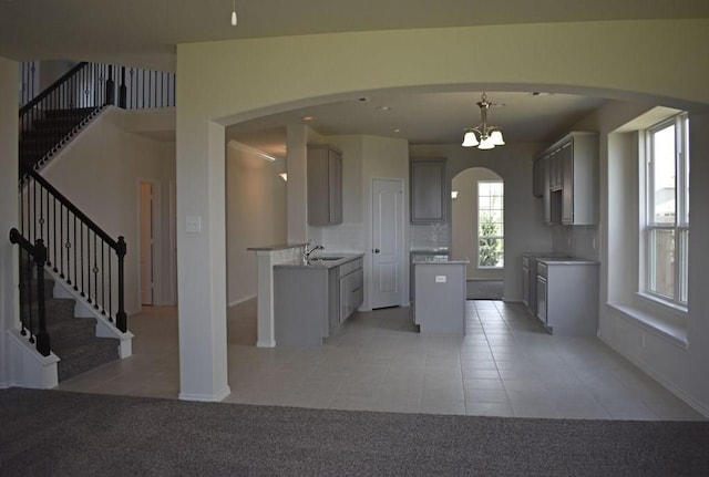 7615 Adobe Canyon Ln, Richmond, TX 77469 - kitchen featuring light tile patterned floors, arched walkways, a kitchen island, and gray cabinets