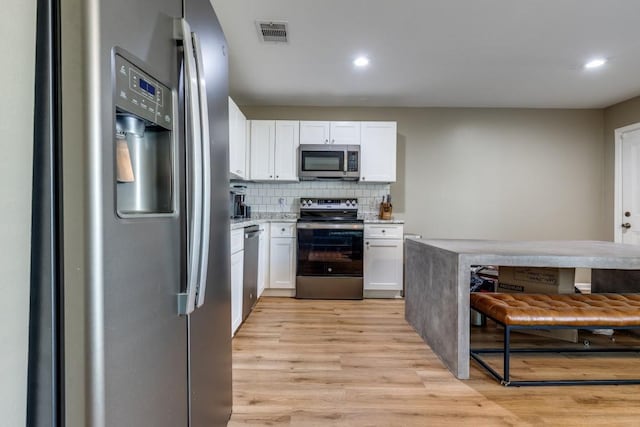 8206 Bassett St, Houston, TX 77051 - kitchen featuring stainless steel appliances, white cabinets, light wood-style floors, recessed lighting, and backsplash