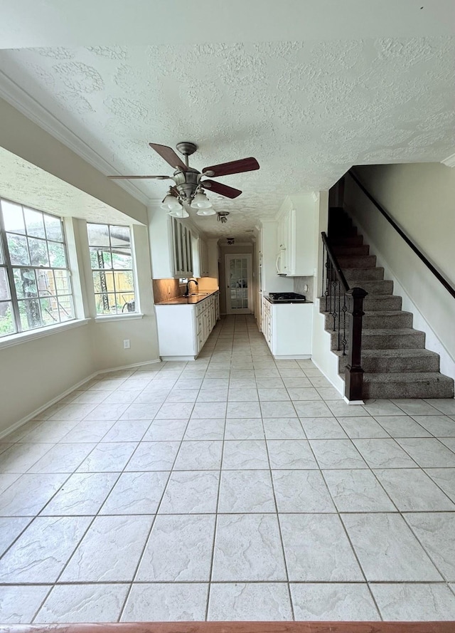 10302 Sageplum Dr, Houston, TX 77089 - unfurnished living room featuring a ceiling fan, a textured ceiling, stairway, ornamental molding, and light tile patterned flooring