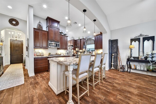 6507 Crystal Forest Trl, Katy, TX 77493 - kitchen featuring stainless steel appliances, high vaulted ceiling, dark wood-type flooring, arched walkways, and dark brown cabinets