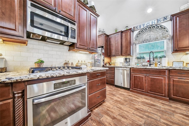 6507 Crystal Forest Trl, Katy, TX 77493 - kitchen featuring stainless steel appliances, light stone counters, light wood-style floors, and backsplash
