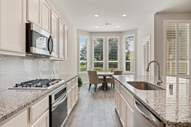 20923 Bradley Gardens Dr, Spring, TX 77379 - kitchen featuring appliances with stainless steel finishes, tasteful backsplash, wood finished floors, recessed lighting, and light stone countertops