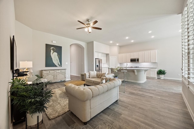 20923 Bradley Gardens Dr, Spring, TX 77379 - living room with arched walkways, light wood-style floors, a ceiling fan, and recessed lighting