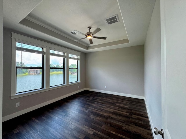 14912 Diamondhead Rd, Conroe, TX 77356 - empty room featuring a tray ceiling, dark wood-style floors, ornamental molding, a ceiling fan, and a water view