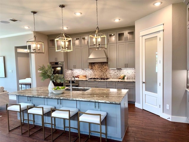 14912 Diamondhead Rd, Conroe, TX 77356 - kitchen with gray cabinets, tasteful backsplash, dark wood finished floors, stainless steel gas stovetop, and ornamental molding
