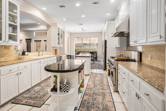 4925 Pine St, Bellaire, TX 77401 - kitchen featuring stainless steel appliances, under cabinet range hood, a center island, recessed lighting, and white cabinets