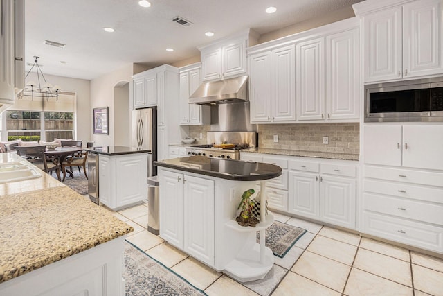 4925 Pine St, Bellaire, TX 77401 - kitchen with stainless steel appliances, under cabinet range hood, a center island, light tile patterned floors, and recessed lighting