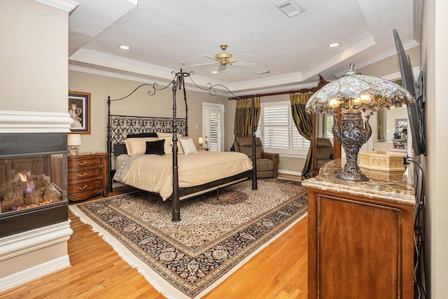 4925 Pine St, Bellaire, TX 77401 - bedroom featuring light wood-style flooring, a tray ceiling, ornamental molding, and ceiling fan