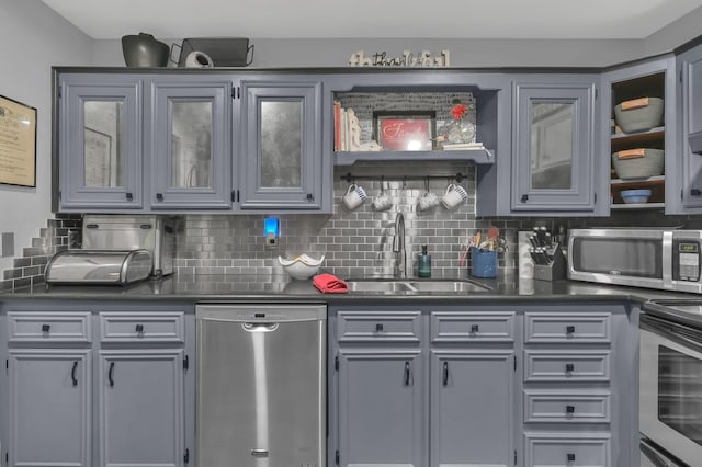 12626 Woodcreek Dr, Willis, TX 77318 - kitchen with appliances with stainless steel finishes, dark countertops, gray cabinets, and tasteful backsplash