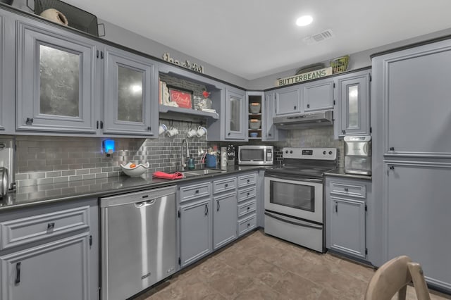 12626 Woodcreek Dr, Willis, TX 77318 - kitchen featuring appliances with stainless steel finishes, under cabinet range hood, dark countertops, and decorative backsplash