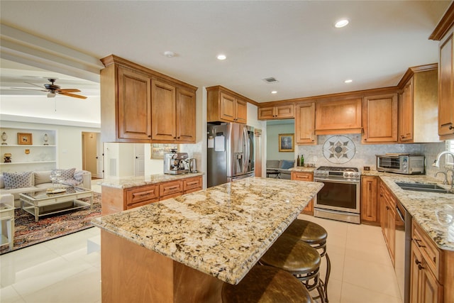 14227 Indian Wells Dr, Houston, TX 77069 - kitchen featuring stainless steel appliances, brown cabinets, light stone countertops, a ceiling fan, and recessed lighting