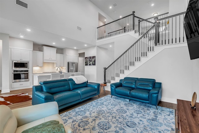 9219 Trimble Landing Dr, Tomball, TX 77375 - living room featuring stairs, wood finished floors, a towering ceiling, and recessed lighting